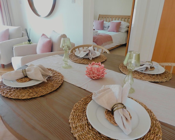 A dining table set with plates, napkins, and glassware, surrounded by woven placemats.