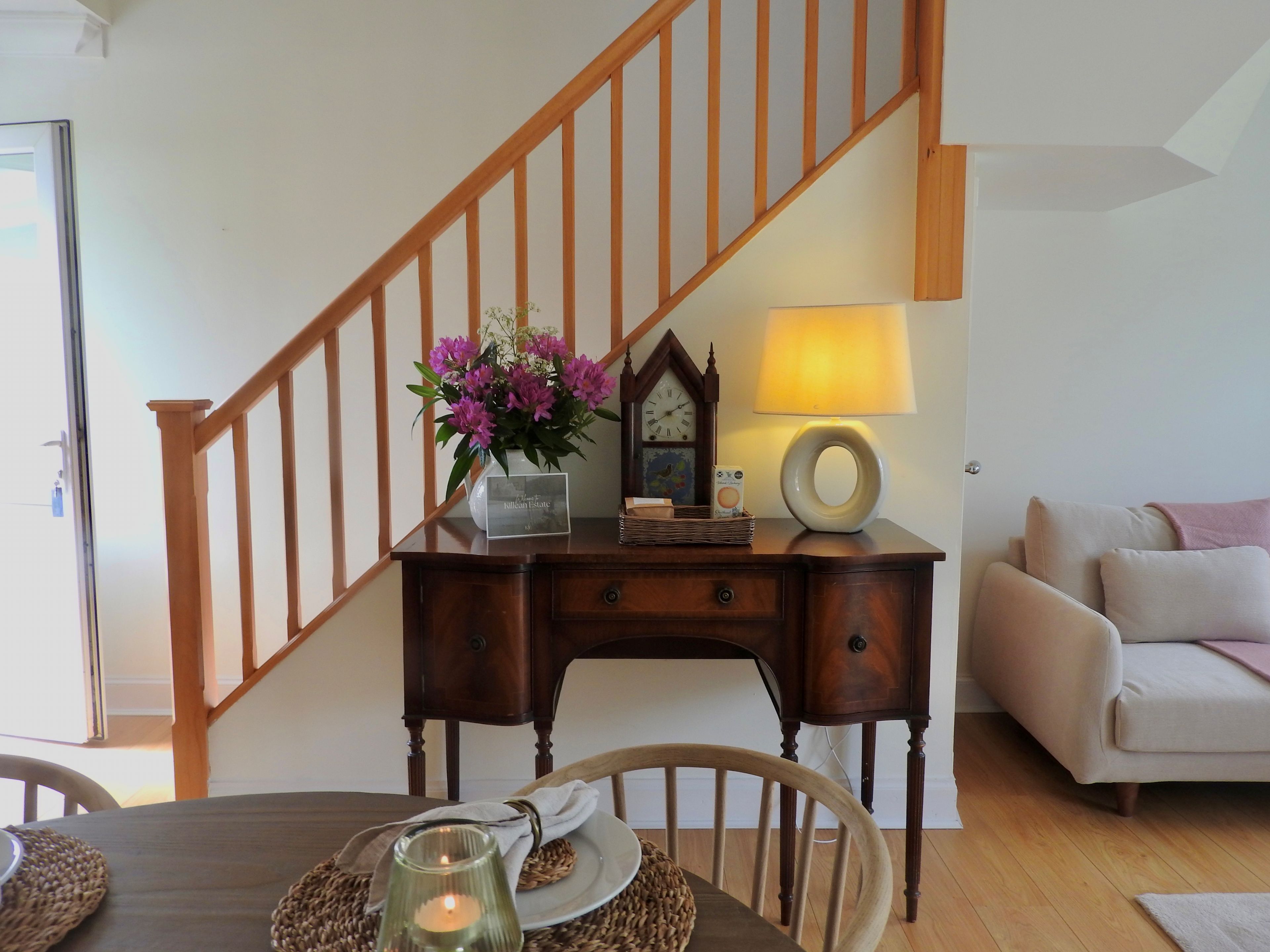 Un coin repas avec un escalier en bois, une table éclairée par une bougie et une lampe.