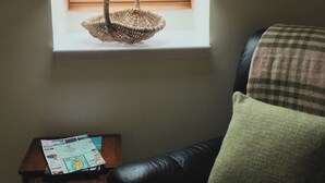 A room with a window, a wicker basket on the sill, a leather chair, and a small table with a map. - Foxglove Cottage - sleeps 4 guests  in 2 bedrooms (Argyll)