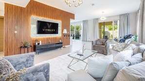 Uma sala de estar moderna com uma TV marca Vivalux, uma mesa de centro de vidro e um sofá macio.
