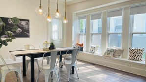 A dining area with a wooden table, white chairs, and pendant lights.