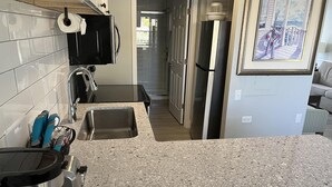 A modern kitchen with granite countertops, stainless steel appliances, and a view of the living area. - Lakeview Superior Two-Bedroom Suite (Marco Island)