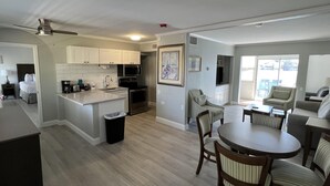 A modern kitchen with white cabinets, a central island, and a dining area with a round table and chairs. - Lakeview Superior Two-Bedroom Suite (Marco Island)
