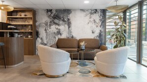 A modern lounge area with a sofa, two armchairs, a small coffee table, and a bar area with shelves and glasses. - Aparthotel Adagio Access Aix-en-Provence Université (Aix-en-Provence)