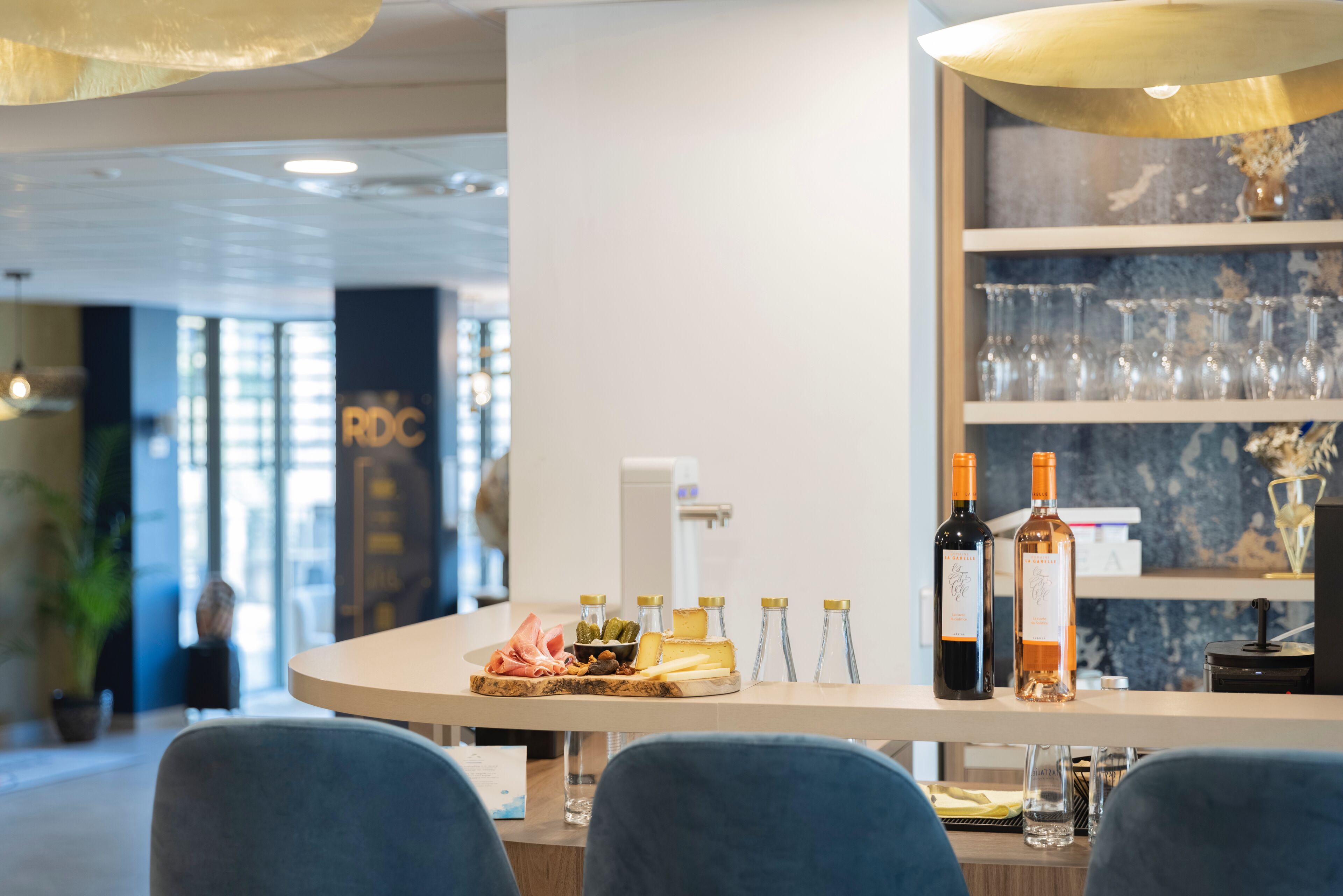 Zona de bar con exhibición de quesos y vinos, asientos y vista del interior.