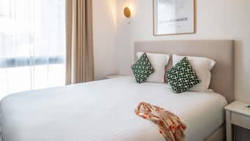 Una habitación de hotel con cama, un mapa en la pared y una ventana con cortinas.