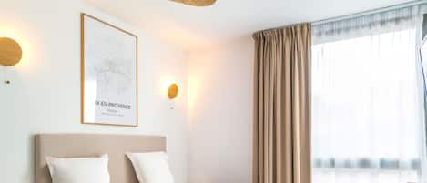 A hotel room with two beds, a map on the wall, and a window with curtains.