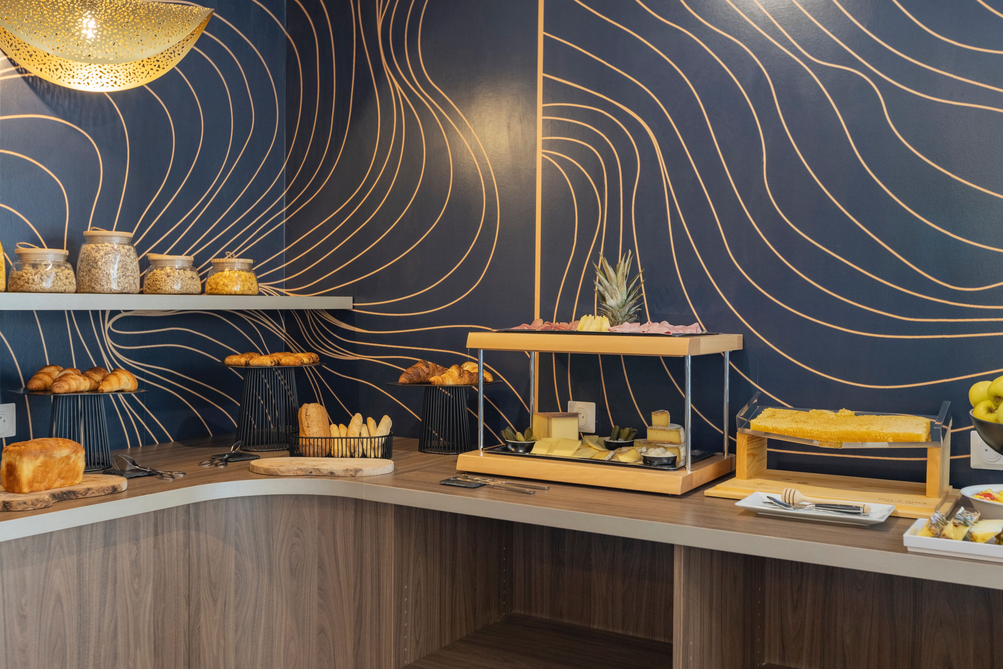 A breakfast buffet with various food items and a decorative wall with wavy lines.