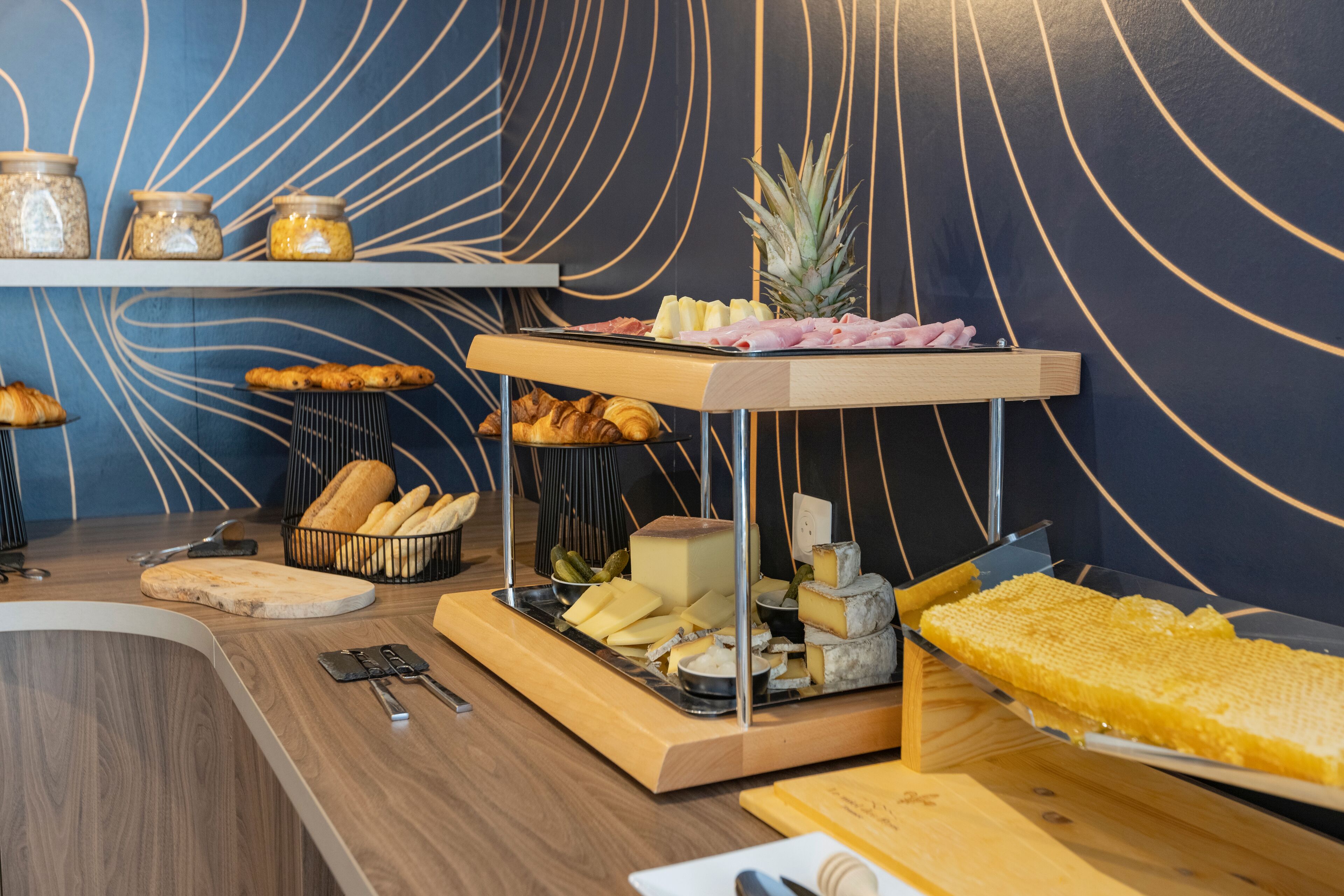 A breakfast buffet with various cheeses, fruits, and pastries.