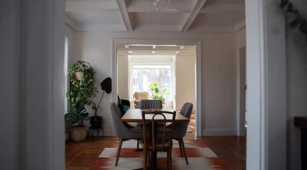 A dining area with a table and chairs, a potted plant, and a view of the outside.