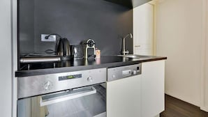 Uma cozinha moderna com bancada preta, eletrodomésticos de aço inoxidável e armários brancos.