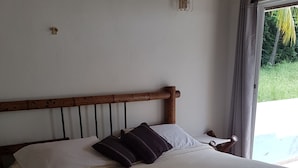 A neatly made bed with white and dark pillows, a wooden headboard, and a small decorative item on the bed. - Playa Tranquilo B&B  (San Andrés)