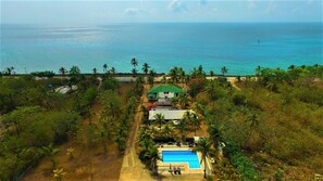 An aerial view of a resort with a swimming pool, palm trees, and a view of the ocean. - Playa Tranquilo B&B  (San Andrés)