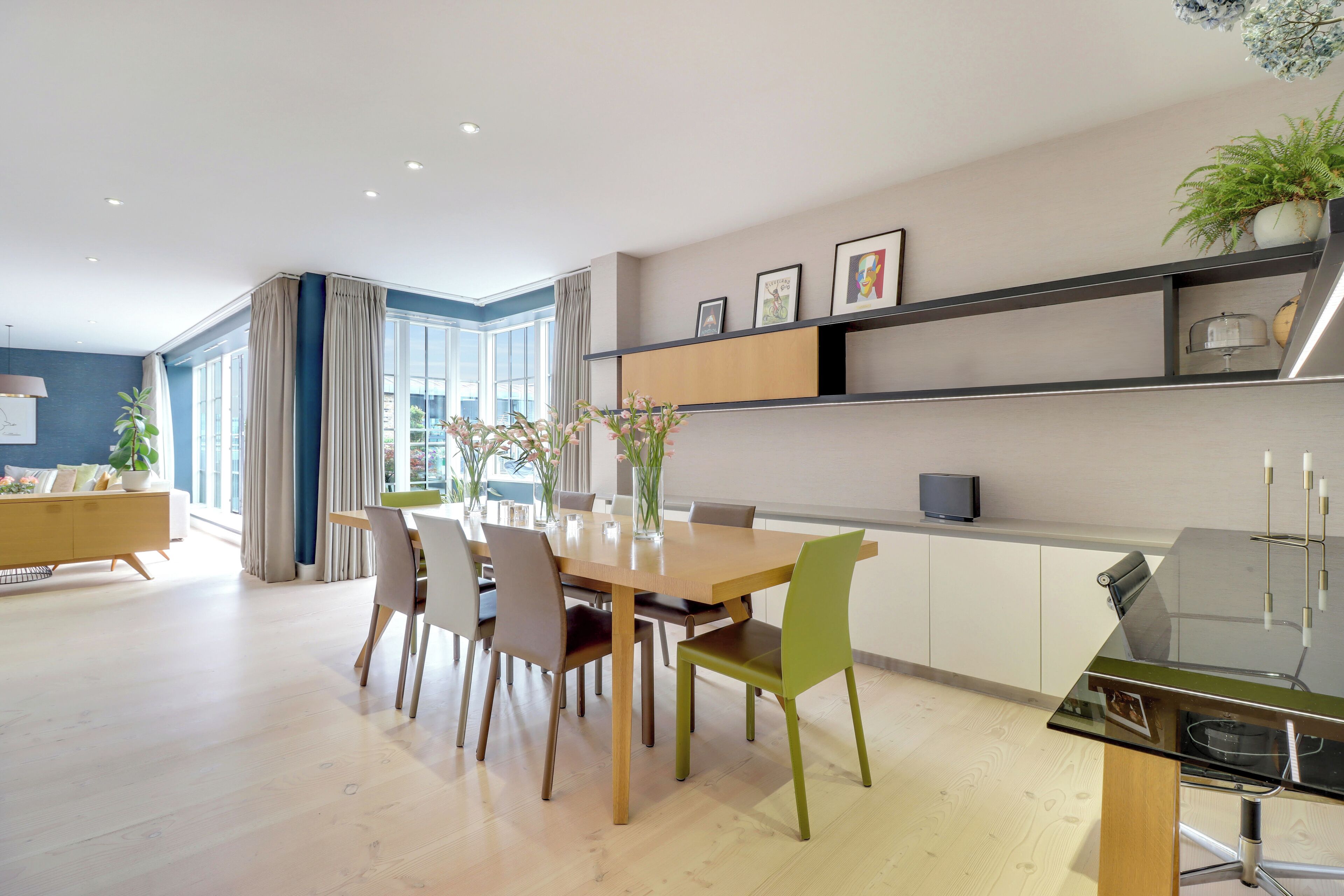 A modern dining area with a wooden table and chairs, a glass coffee table, and a built-in shelf with decorative items.