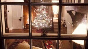 Un intérieur à plusieurs niveaux, agrémenté d’un sapin de Noël, d’une cheminée et d’un lustre.