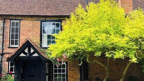 Une maison traditionnelle en briques, avec une porte en bois foncé et des fenêtres à cadre blanc.
