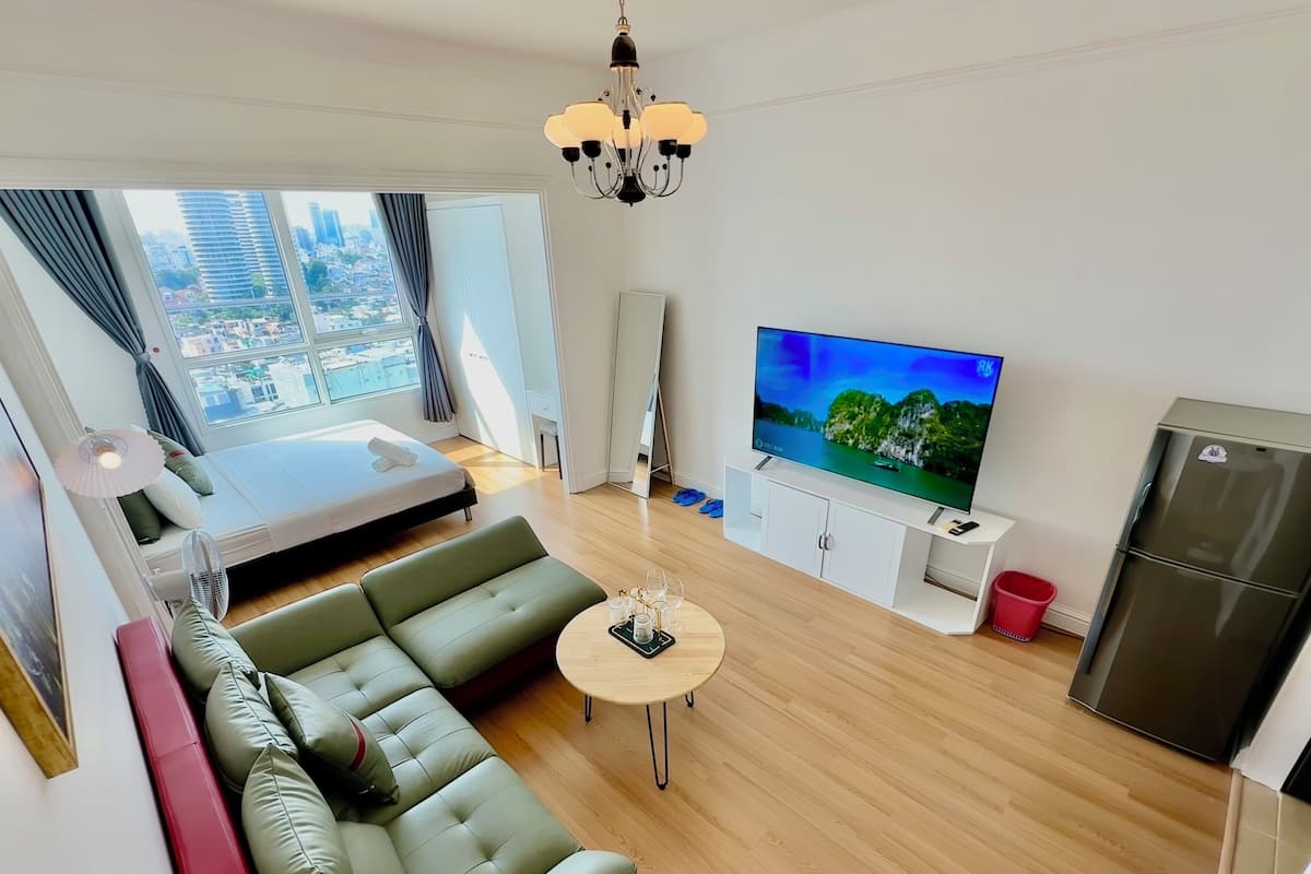 A modern living room with a sofa, a small round table, a TV, and a refrigerator.