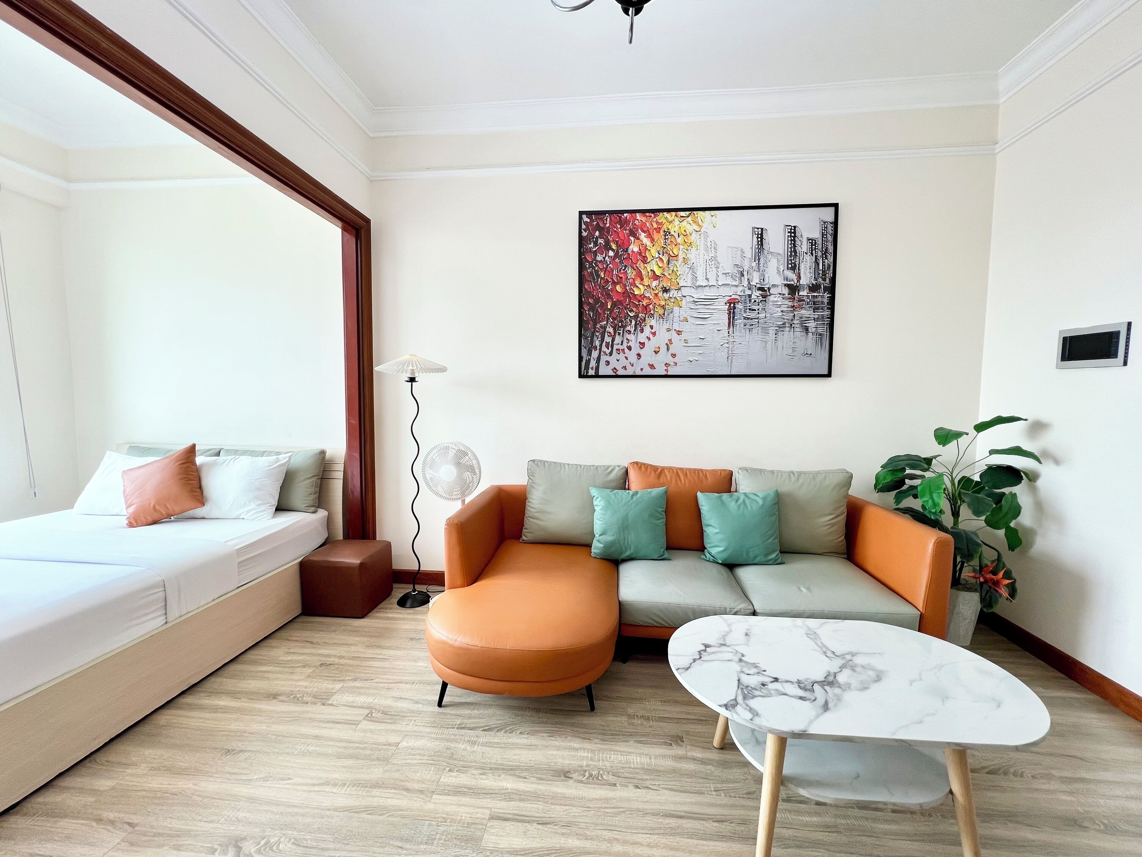 A modern living room with a sofa, a coffee table, a floor lamp, and a painting on the wall.