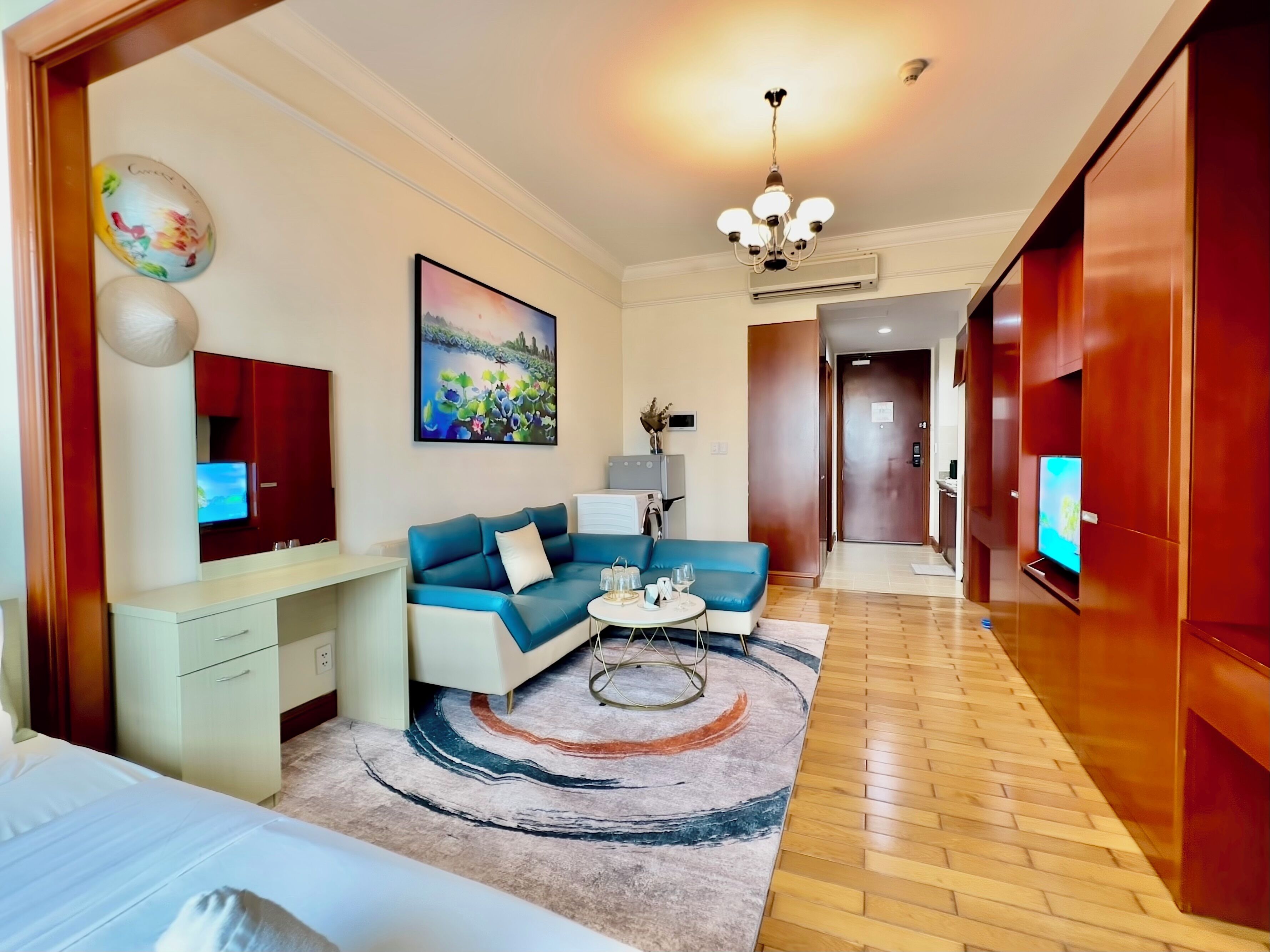 Una moderna camera d'albergo con divano, un tavolino, televisione e un quadro appeso al muro.
