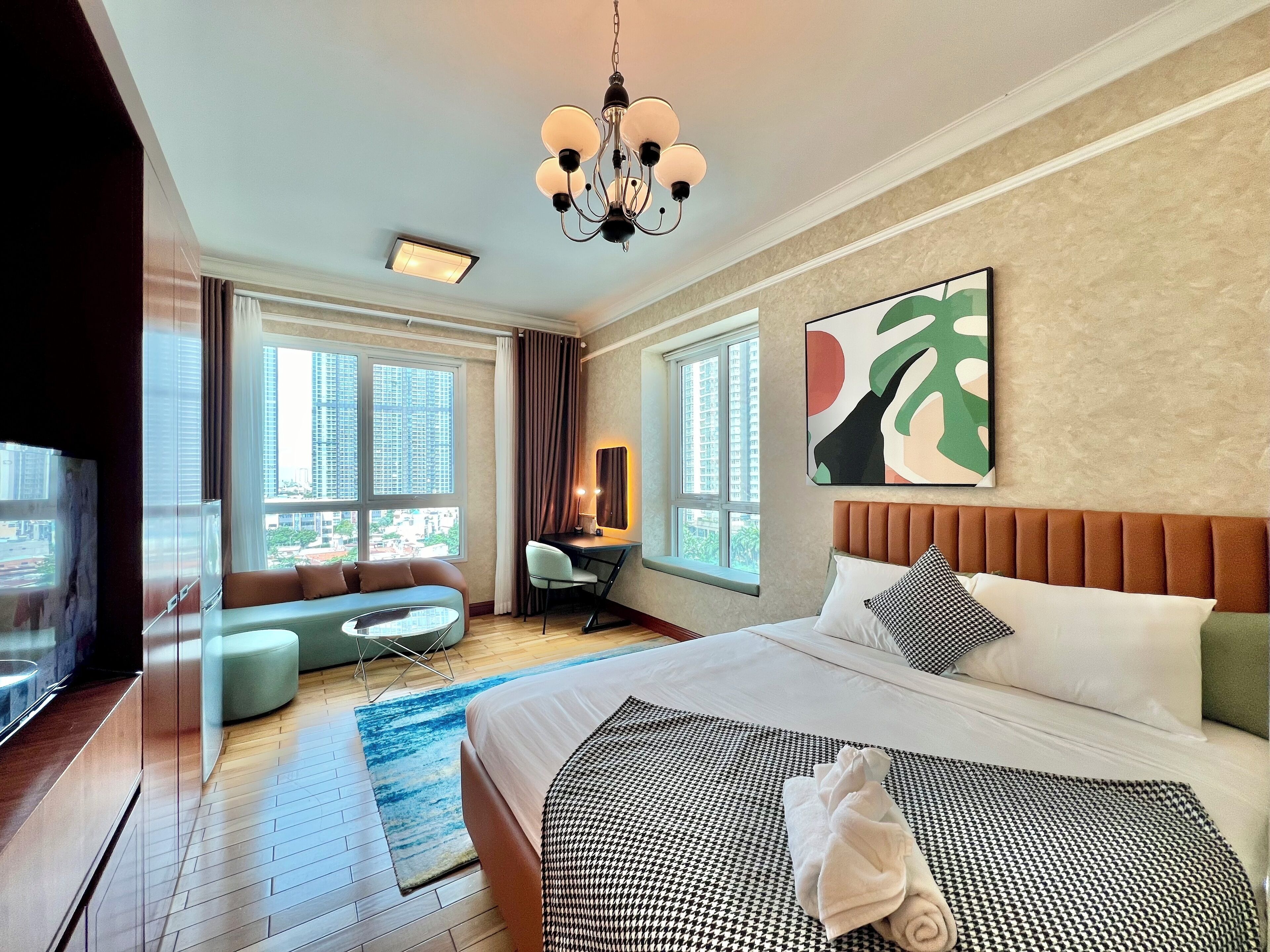 A modern hotel room with a large bed, a sofa, a desk, and a TV.