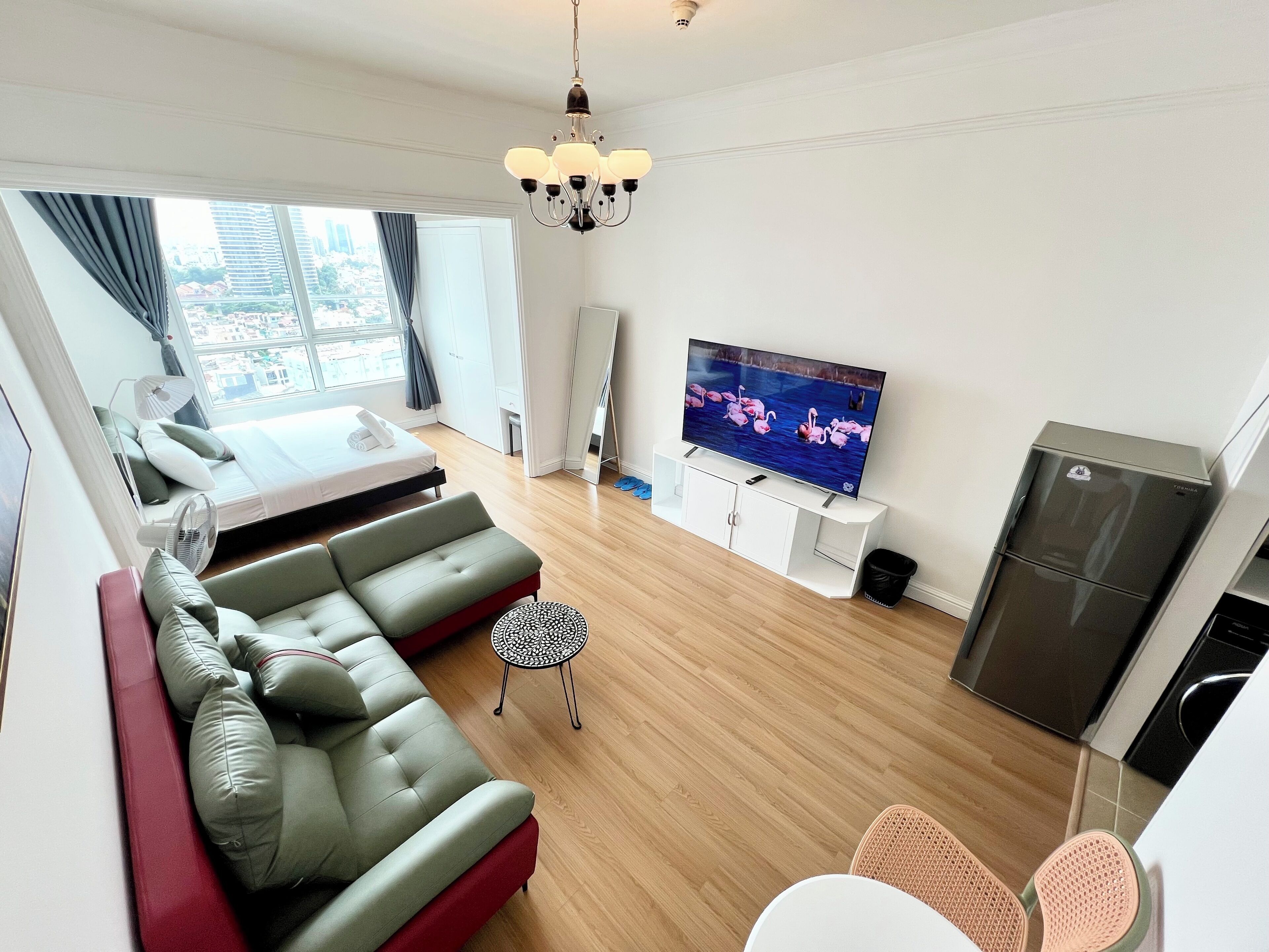 A modern living room with a sofa, TV, and a refrigerator.