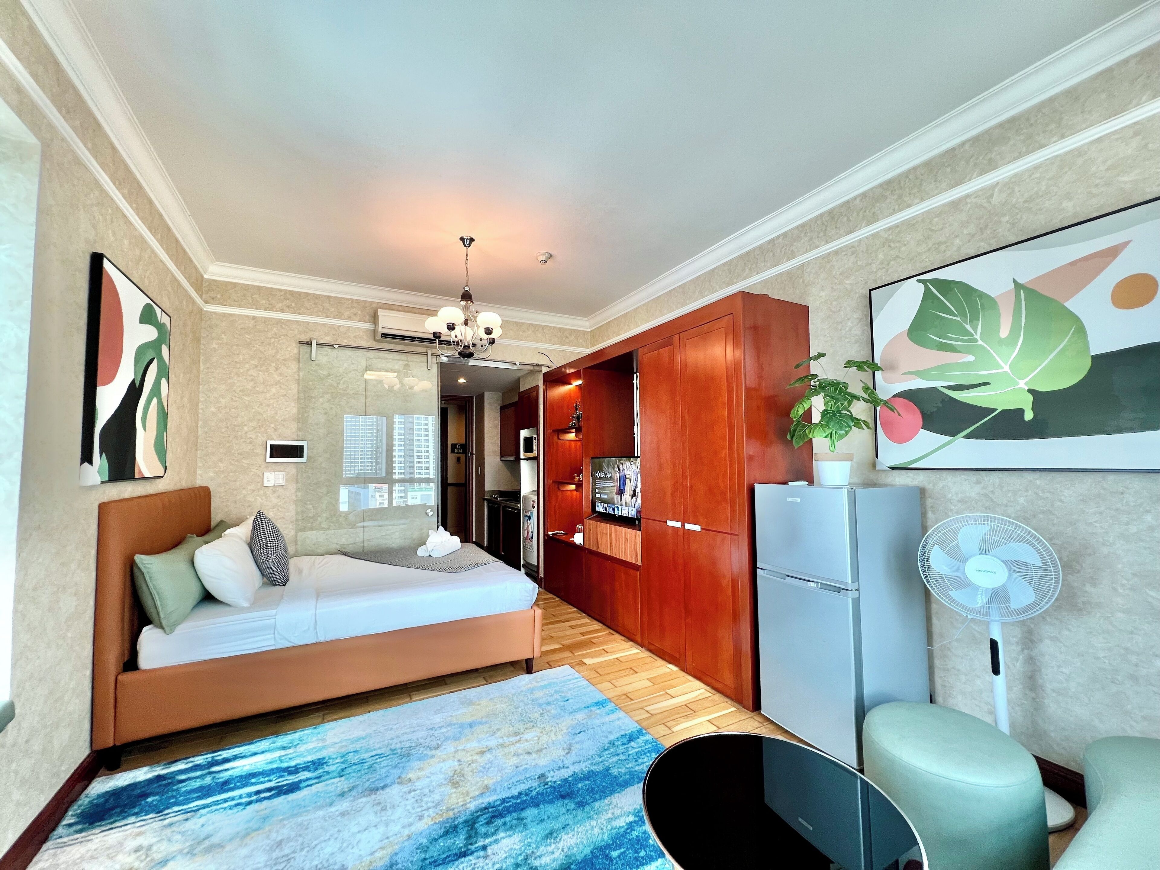 Ein modernes Hotelzimmer mit Bett, Schreibtisch, Küchenzeile und großem Fenster.