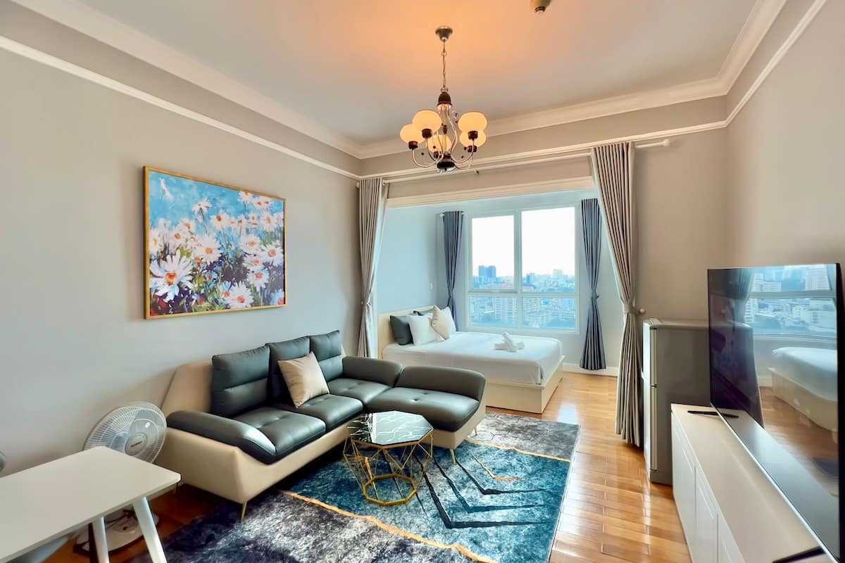 A modern living room with a sofa, a coffee table, a TV, and a painting on the wall.