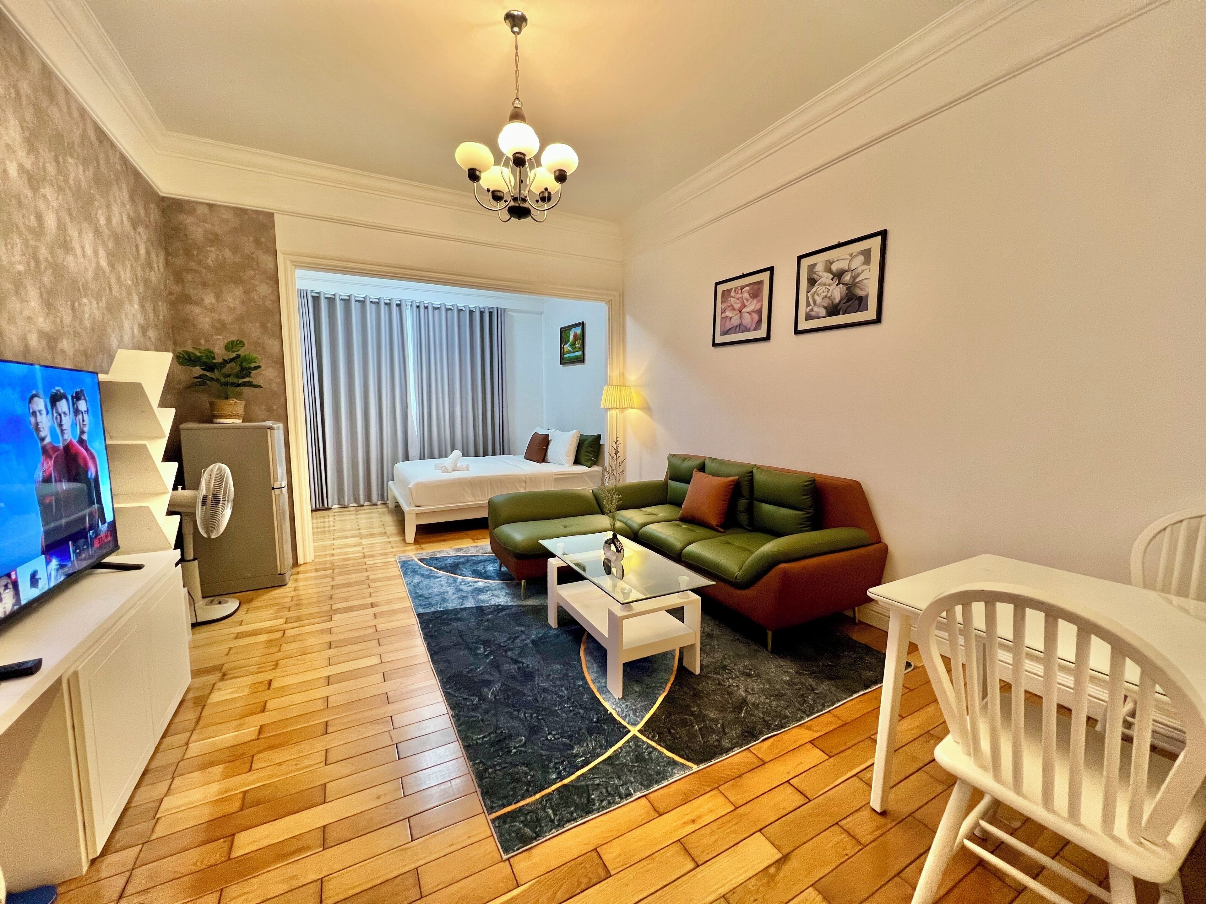 A modern living room with a sofa, coffee table, TV, and a fan.