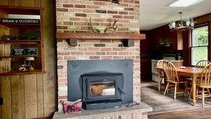 Ein rustikaler Innenraum mit Kamin aus Ziegelsteinen, Holzmöbeln und Deckenventilator.