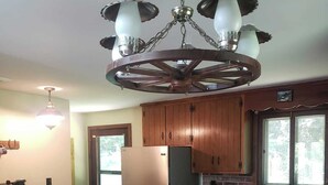 Eine Küche mit Holzausstattung, einem Edelstahlkühlschrank, einem Holzespeise Tisch mit Stühlen und einer Kandelaber.