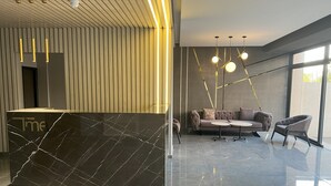 Ein moderner Empfangsbereich mit einer Marmorrezeption, einer Couch und Pendelleuchten.