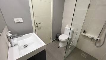 Un baño moderno con lavamanos, inodoro y cabina de ducha de vidrio.