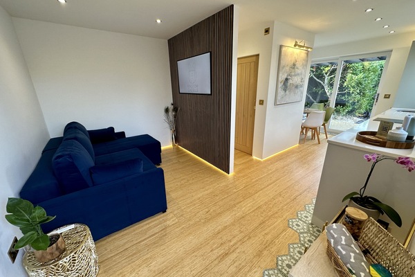 Living room with double sofa bed, 50" Samsung Smart TV, and LED accent lighting.