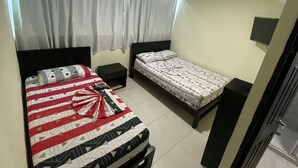 Un dormitorio con dos camas, una mesita de noche, un televisor y una ventana con cortinas.