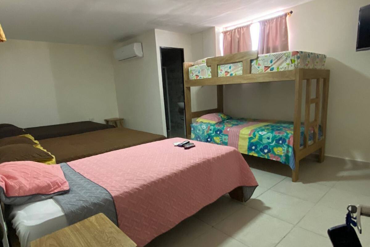 A dormitory room with bunk beds, a desk, and a chair.