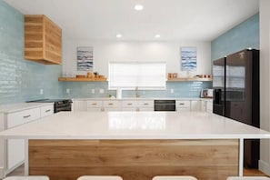 Una cocina moderna con una isla grande, armarios de madera y un horno empotrado.