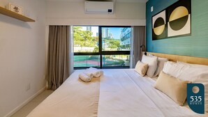 Une chambre d’hôtel moderne avec un grand lit, une vue sur la ville et un mur d’accent bleu.