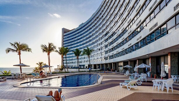 Un espace piscine d’hôtel comprenant des chaises longues, des parasols et une piscine.