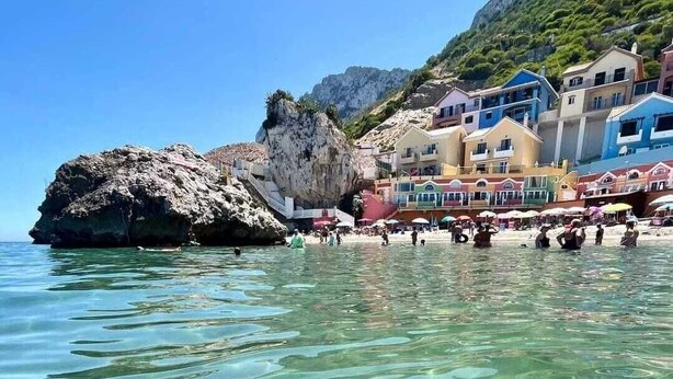 Une ville côtière aux bâtiments aux couleurs vives, aux eaux d’un bleu limpide et aux falaises rocheuses.