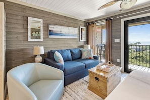 Relax in a stylish room with a sofa, armchair, and wooden chest of drawers, plus a large window with a view.