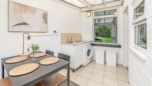 Una cocina funcional con lavadora, una mesa de comedor con individuales y un cuadro abstracto grande en la pared.