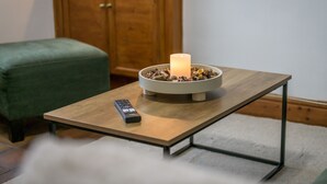 Una mesita con un control remoto y una vela en un recipiente.