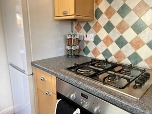 Kitchen features a gas stove with four burners, stainless steel oven, and a digital clock.