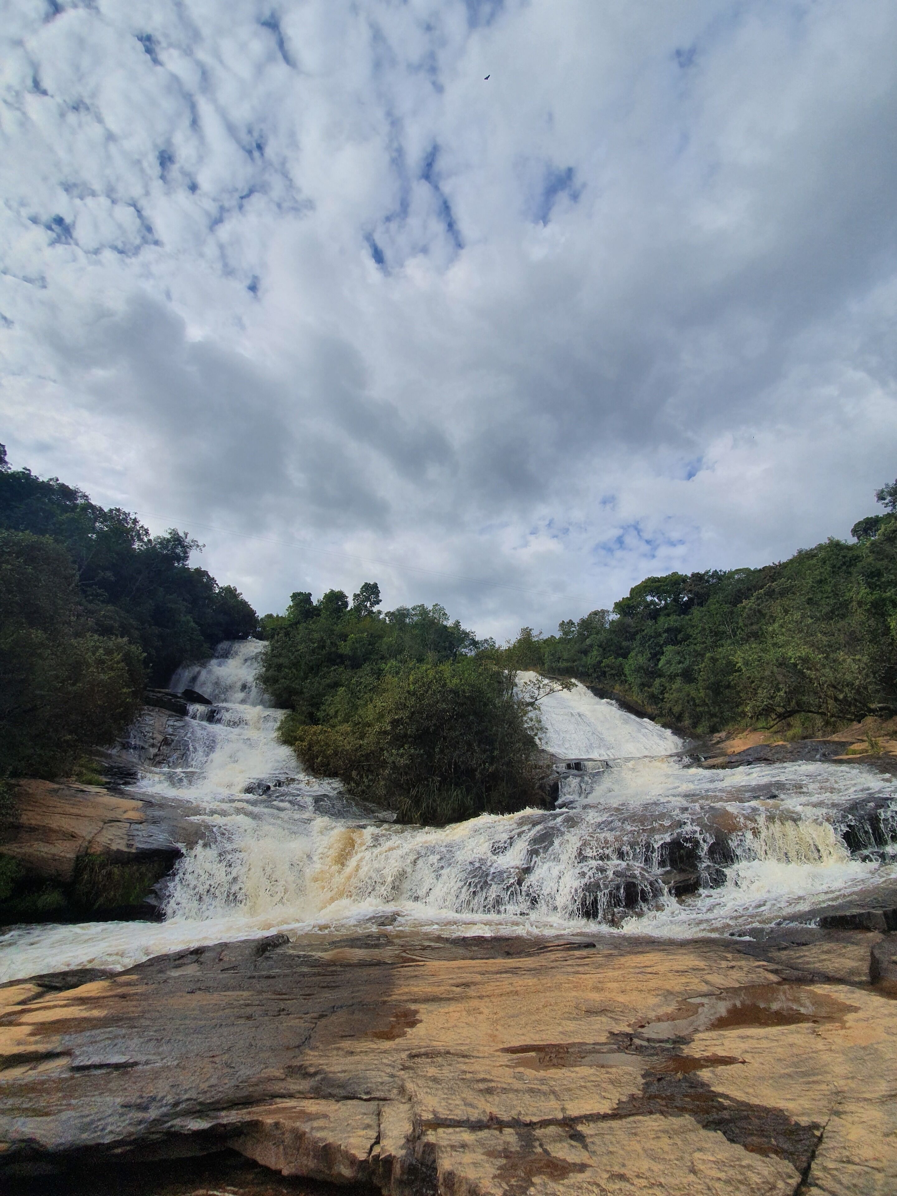 Une cascade d’eau se déversant sur des rochers, entourée d’une végétation luxuriante.