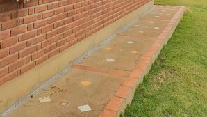Un edificio de ladrillo con contraventanas de madera y techo de tejas.