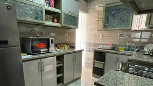 Una cocina con electrodomésticos de acero inoxidable, microondas y encimeras de granito.