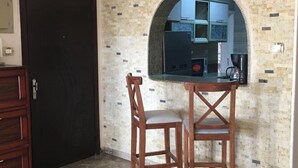 Una cocina con protector de piedra, una puerta negra y dos sillas de madera.