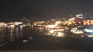 A nighttime cityscape with illuminated buildings and a body of water.