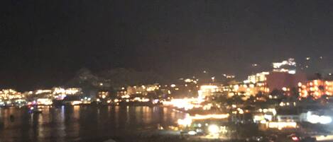 A nighttime cityscape with illuminated buildings and a body of water.