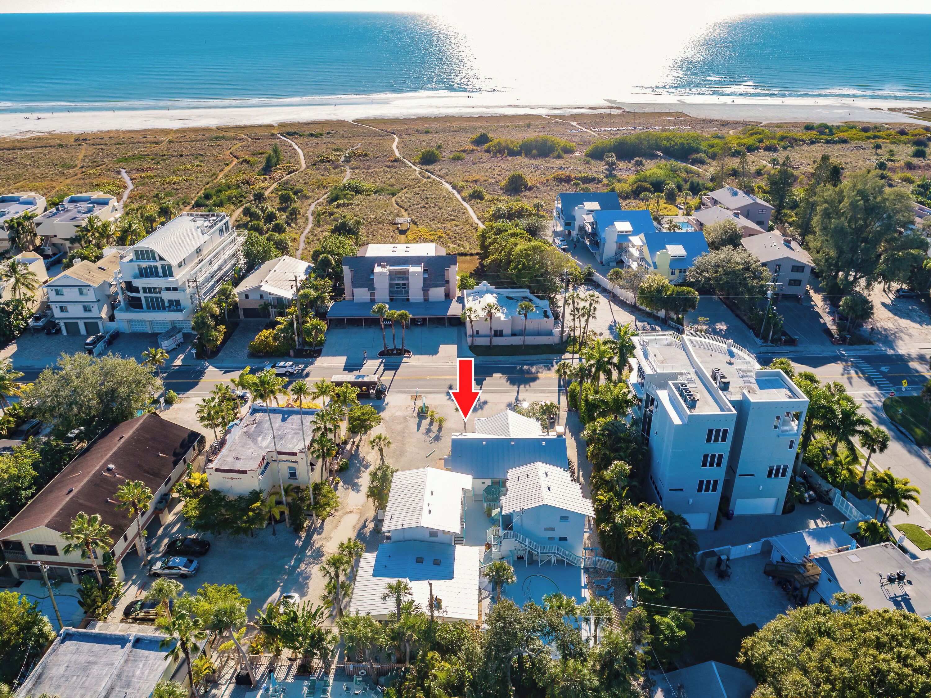 An aerial view of a coastal residential area with buildings, roads, and a beach.